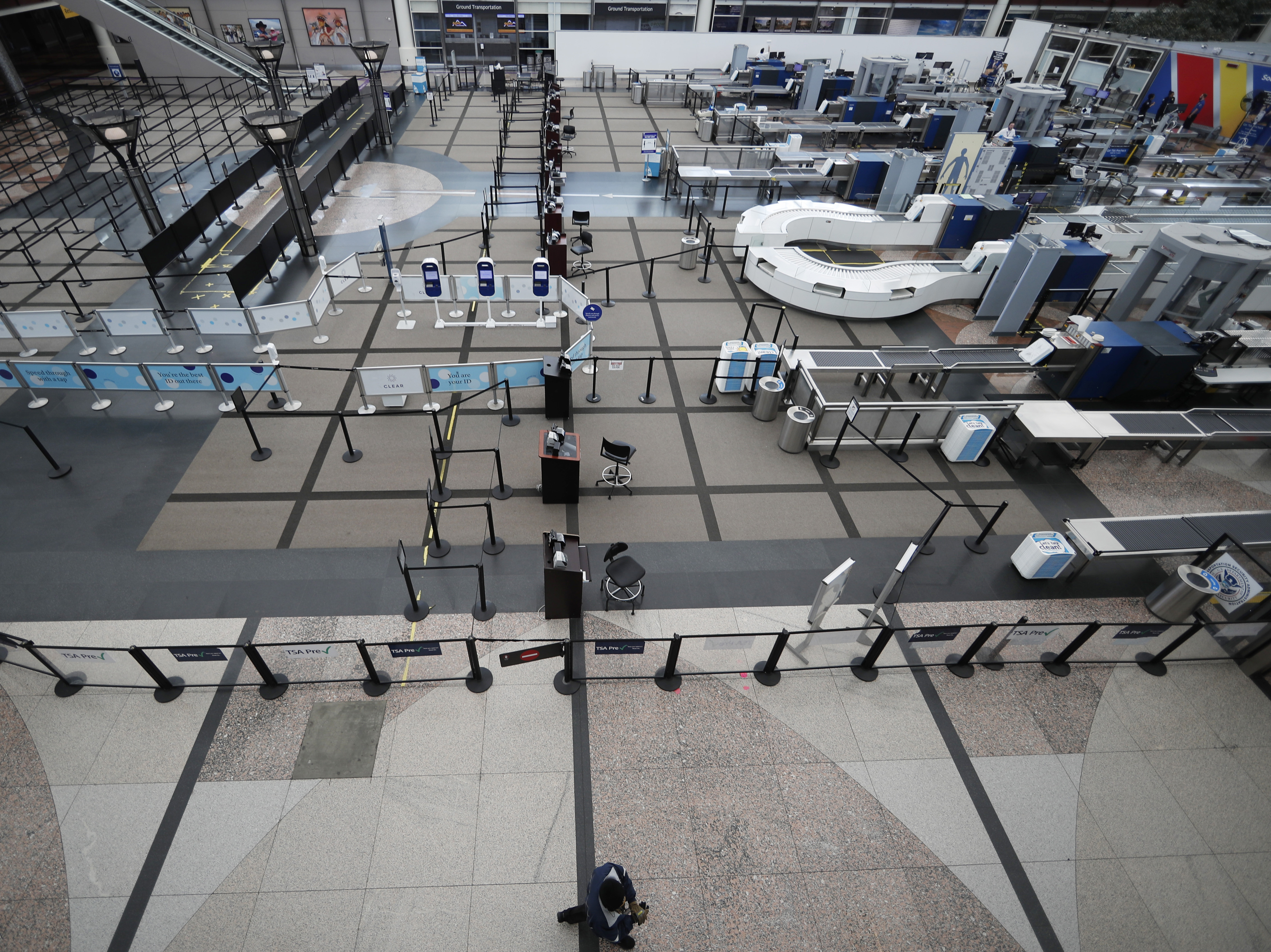 caption: A lone passenger walks past the north checkpoint at Denver International Airport on April 1, which was closed because of a lack of traffic as a statewide stay-at-home order remains in effect to help reduce the spread of the coronavirus.
