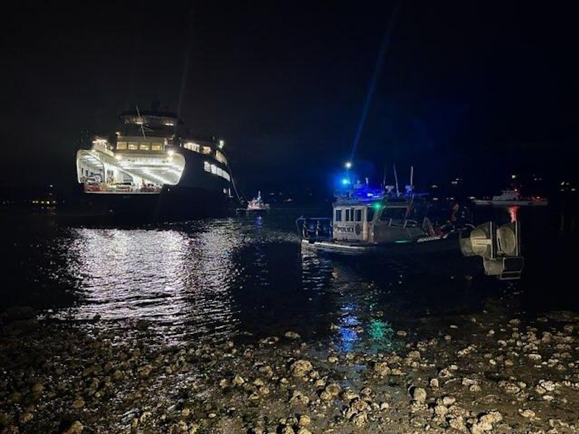 caption: The M/V Walla Walla is towed away at high tide around midnight, April 16, 2023, after the ferry boat ran aground at south Bainbridge Island. 