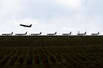 caption: A Southwest Airlines flight takes off as United Airlines planes sit parked on a runway at Denver International Airport in April.