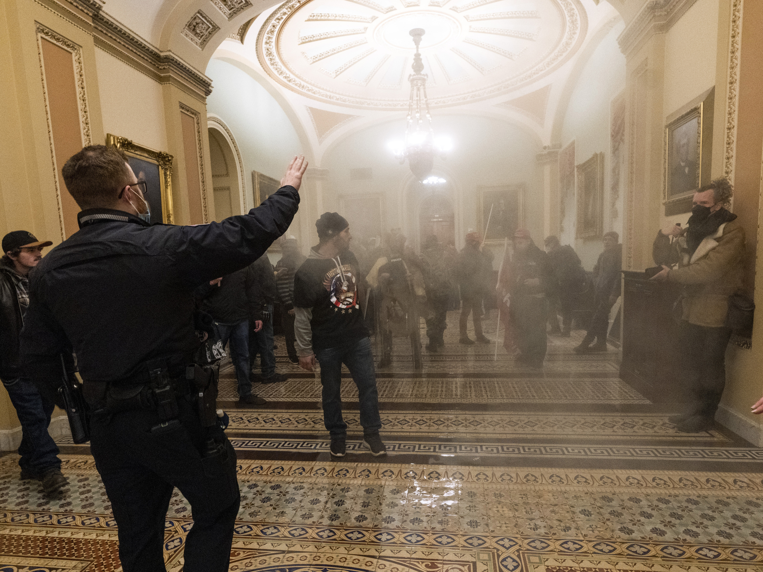 caption: Smoke fills the walkway outside the Senate Chamber as rioters are confronted by U.S. Capitol Police officers inside the Capitol in Washington on Jan. 6.
