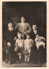 caption: Becky Benaroya (née Benoun) as a child (front center) with her grandfather Yosef, mother Dona, father Judah, brother Sam, and sister Nellie.