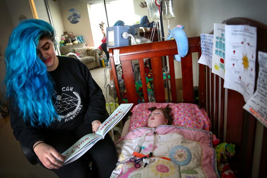 caption: Teal Victoria reads to her 3-year-old daughter Kai at their northeast Seattle home. Kai is on a ventilator and is cared for around the clock at home by her mother and her nurses.