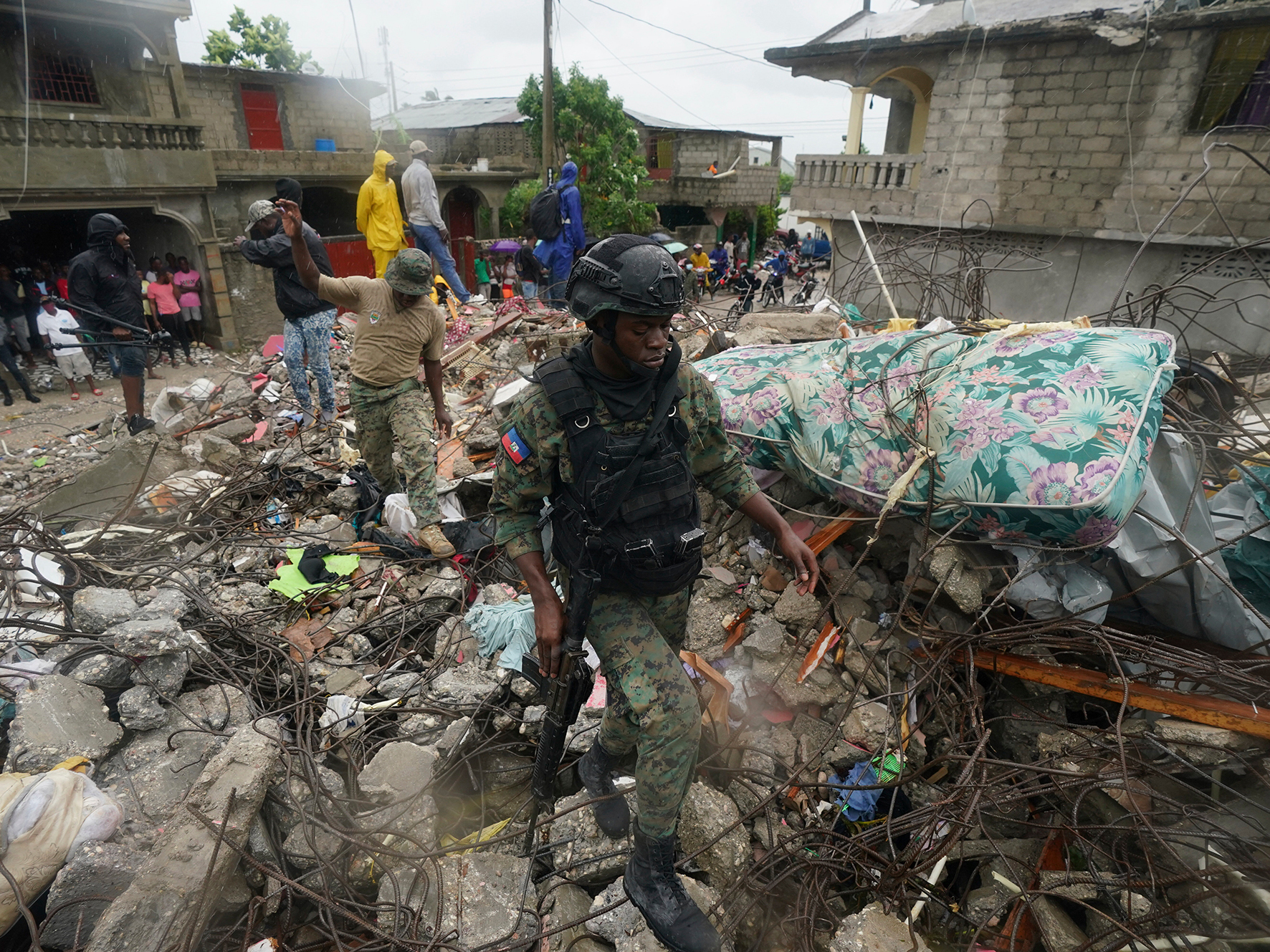 caption: A soldier walks over earthquake rubble on Tuesday, the morning after Tropical Storm Grace swept over Les Cayes, Haiti, three days after the 7.2 magnitude quake.