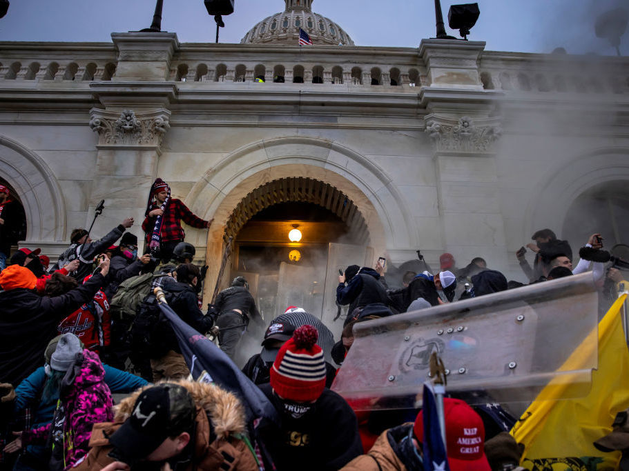 caption: Pro-Trump rioters clash with police and security forces as people storm the U.S. Capitol on Jan. 6. Federal investigators say they expect even more people will be charged in connection with the insurrection.