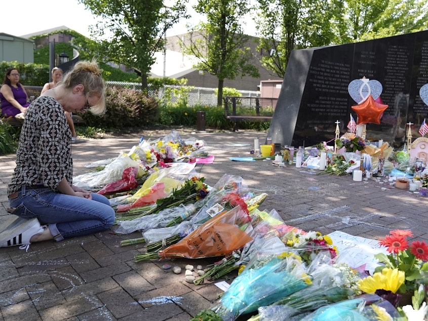 caption: FILE - A visitor prays at a memorial to the seven people killed and others injured in the Fourth of July mass shooting at the Highland Park War Memorial in Highland Park, Ill.