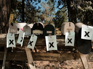 caption: A row of mailboxes tagged with evacuation notices during the Oak Fire in Mariposa, Calif., in July 2022. Many residents in the area are losing their home insurance because of rising wildfire risk.