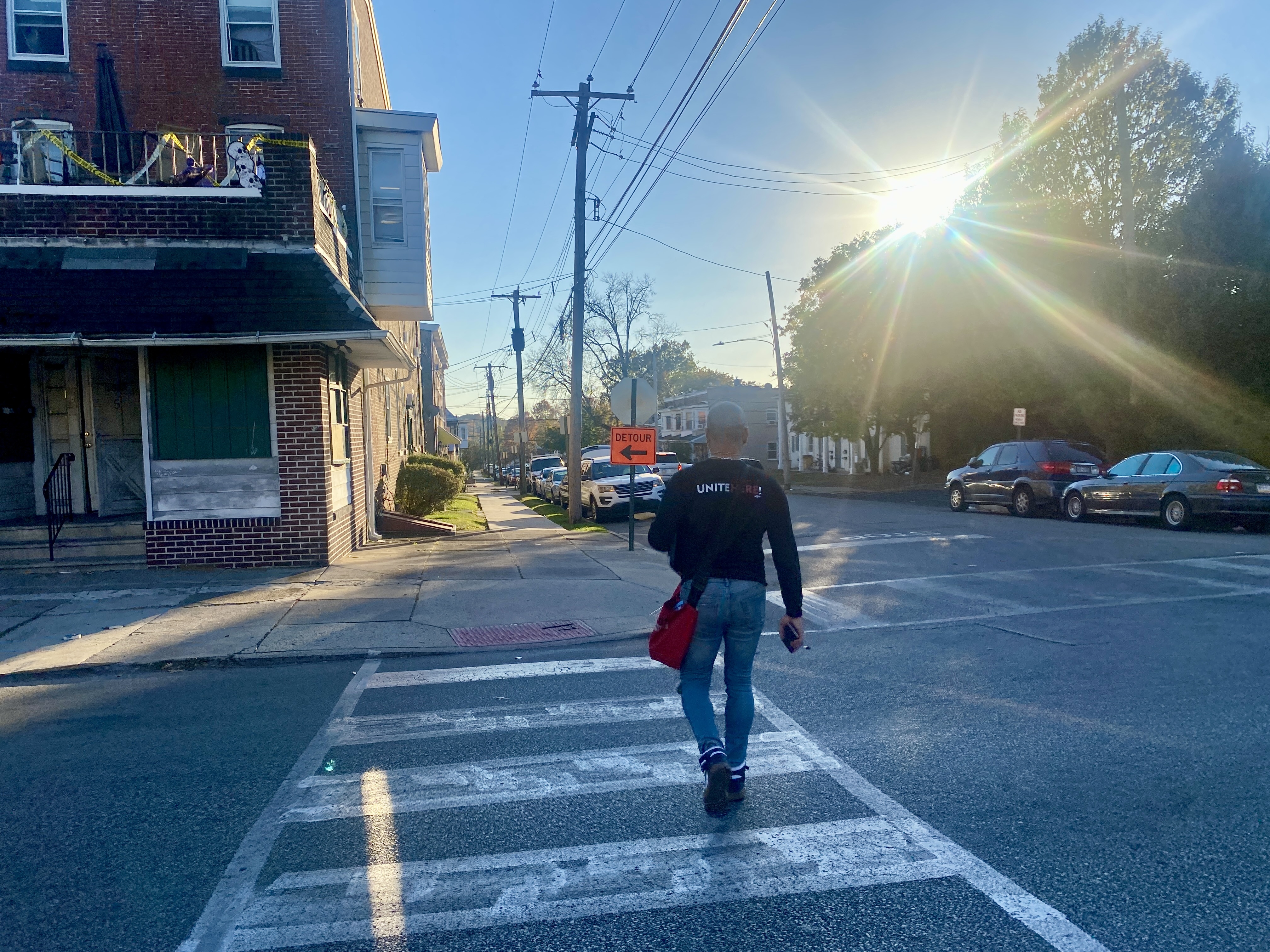 caption: UNITE HERE canvasser Wernel Martinez crosses a street in the Philadelphia suburb of Norristown after a long day of knocking on voters' doors.