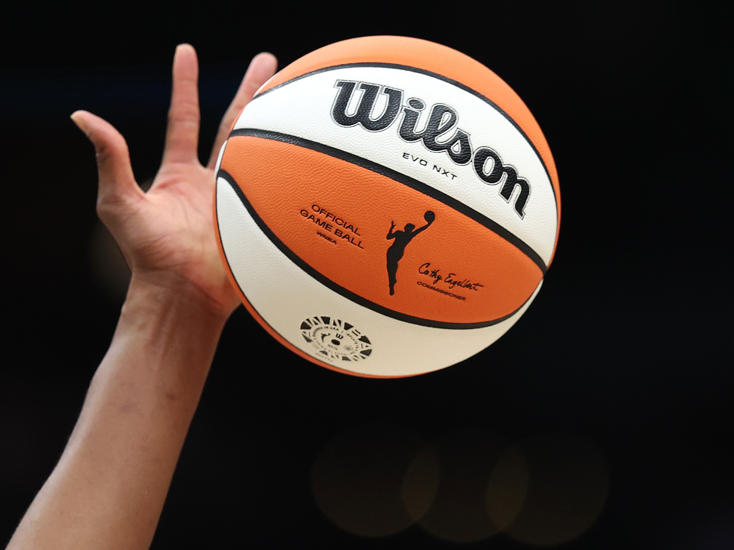 caption: The WNBA logo on the ball is seen as it is tipped during the game between the Seattle Storm and the Las Vegas Aces last year in Seattle, Wash. The WNBA has announced it's expanding to a record 18 teams — adding three new franchises: Cleveland, Detroit and Philadelphia.