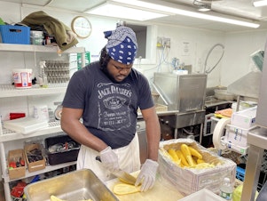 caption: Jason Brissett, a kitchen worker who came to the U.S. last month from Jamaica through an H-2B visa, is bracing for 80-hour work weeks this summer, to help make up for staffing shortages.