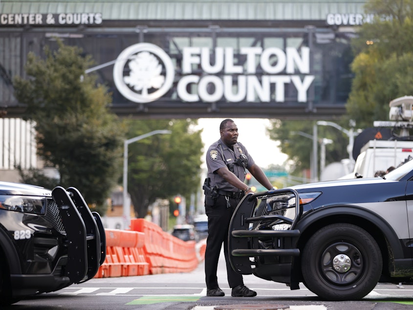 caption: A sheriff's deputy stands guard near the Fulton County Courthouse in Atlanta on Monday. Authorities in Georgia said Thursday they're investigating threats targeting members of the grand jury that indicted former President Donald Trump and 18 of his allies.