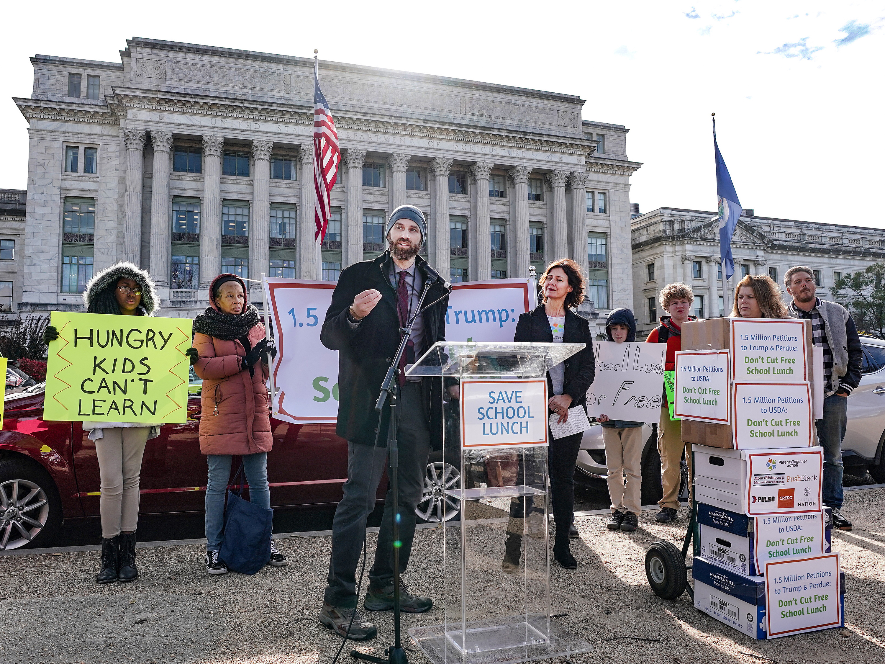 caption: Justin Ruben of ParentsTogether speaks on Thursday at a press conference organized to deliver 1.5 million petitions to the U.S. Department of Agriculture. The petitions are protesting proposed changes to the food stamps program that would also affect the free school lunch program.
