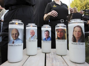 caption: In this June 29, 2018, file photo, pictures of five employees of the <em>Capital Gazette</em> newspaper adorn candles during a vigil across the street from where they were slain in the newsroom in Annapolis, Md.