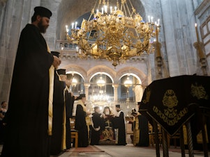caption: A memorial and prayer service at the Church of the Holy Sepulchre in Jerusalem is held in honor of the victims of an Israeli airstrike at a Gaza church. Bottom left: People attend the special prayer. Bottom right: A man takes communion before the prayer.
