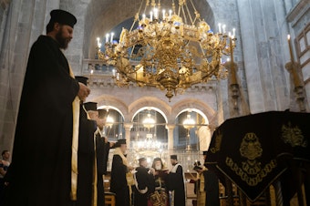 caption: A memorial and prayer service at the Church of the Holy Sepulchre in Jerusalem is held in honor of the victims of an Israeli airstrike at a Gaza church. Bottom left: People attend the special prayer. Bottom right: A man takes communion before the prayer.