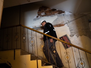 caption: Yasin Pinarbasi walks into a building he inspected that suffered some earthquake damage, west of Antakya, Turkey.