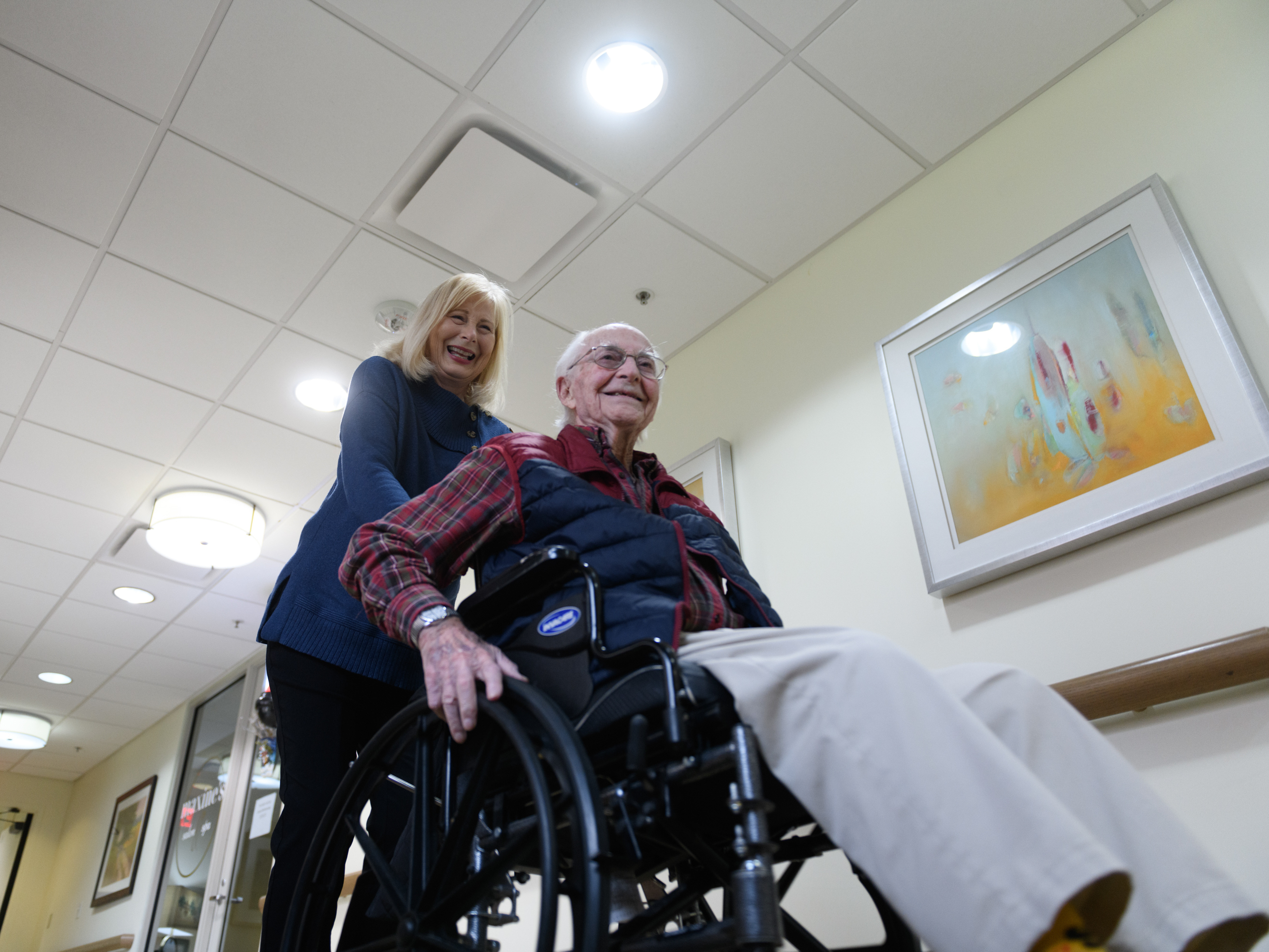 caption: Paula Naylor pushes her father, Paul Romanello, with his wheelchair on Dec. 21 in Tulsa, Okla. Romanello was recently celebrated by the Centenarians of Oklahoma when he turned 100 years old.
