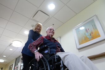 caption: Paula Naylor pushes her father, Paul Romanello, with his wheelchair on Dec. 21 in Tulsa, Okla. Romanello was recently celebrated by the Centenarians of Oklahoma when he turned 100 years old.