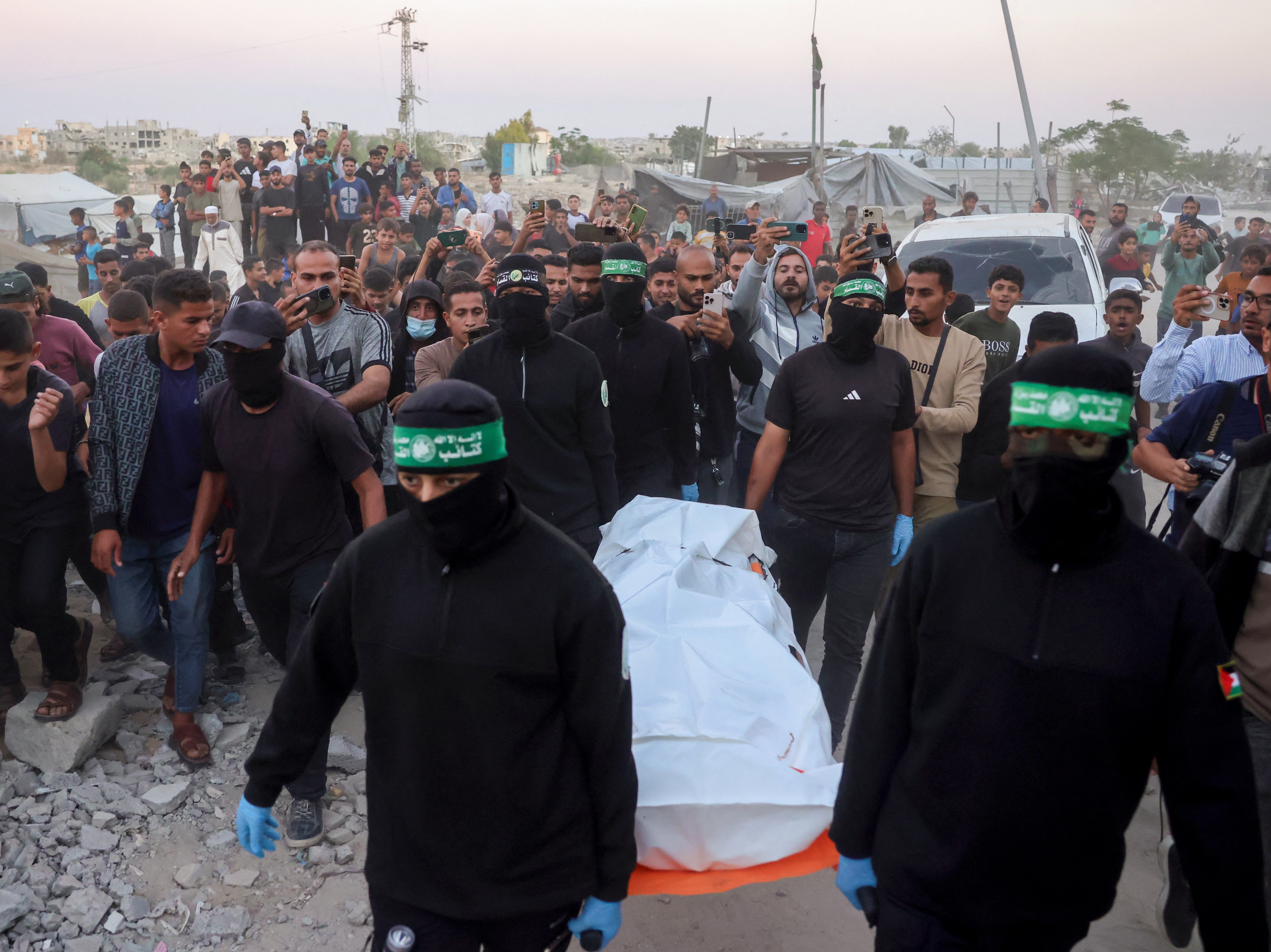 caption: Hamas members carry a body retrieved from a tunnel in an area north of Khan Younis, in the southern Gaza Strip, on Tuesday. Israel accused Hamas of staging its search for the remains of a Gaza hostage body.