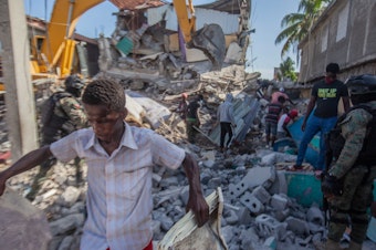 caption: Haitians in Les Cayes assess the damage Sunday after a magnitude 7.2 earthquake struck a day earlier.