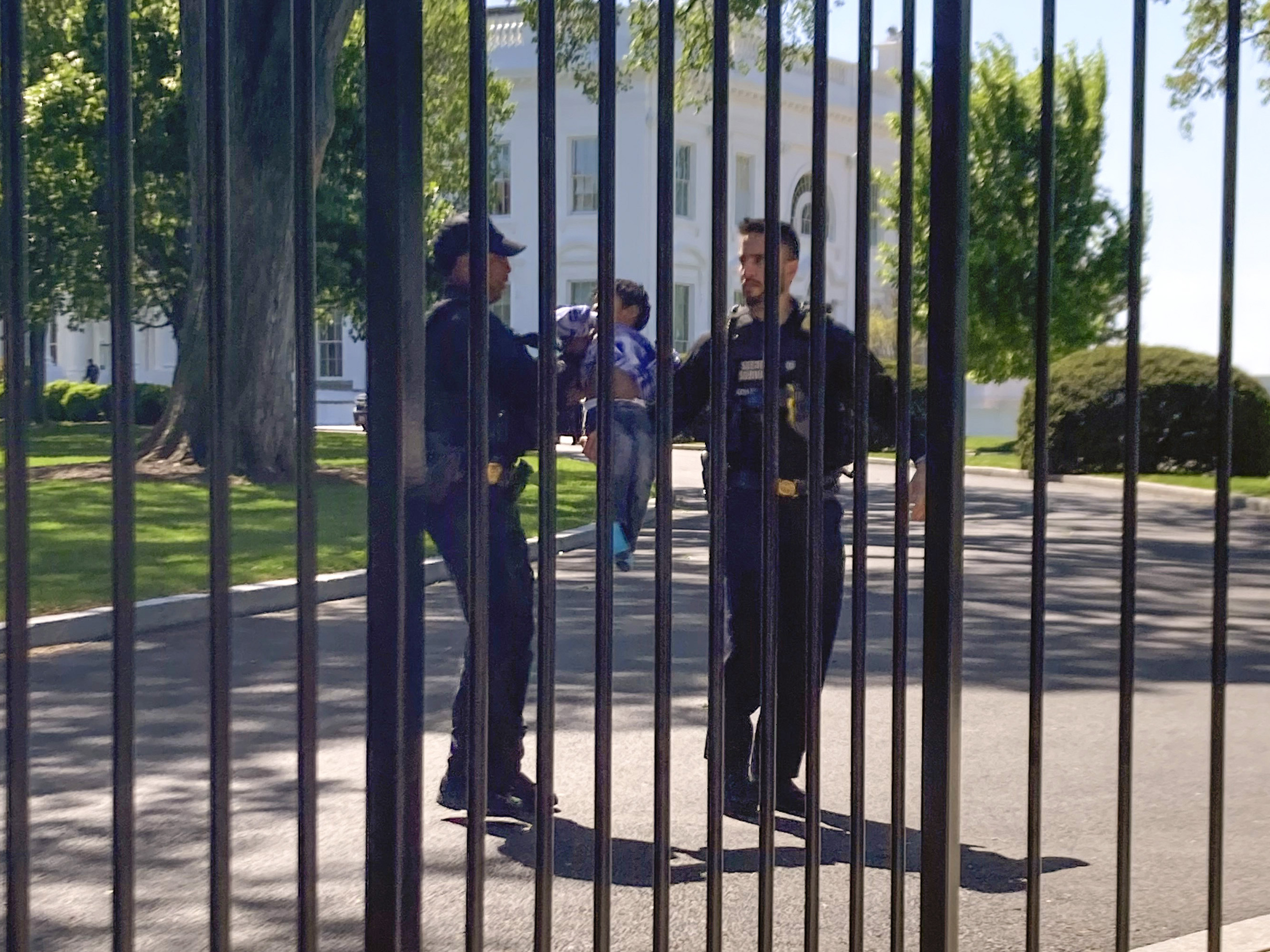caption: U.S. Secret Service uniformed division police officers carry a young child who crawled through the White House fence on Pennsylvania Avenue in Washington on Tuesday.