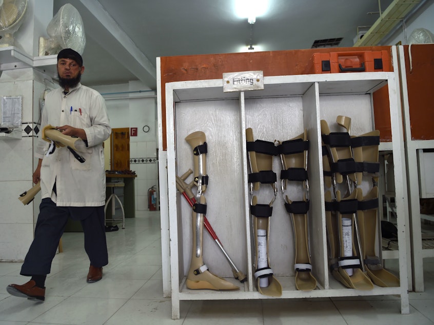 caption: The Taliban says the Red Cross may resume its work in Afghanistan, nearly six months after threatening the group. In this photo from March, an orthopedic technician walks past artificial limbs in a workshop at the International Committee of the Red Cross hospital for war victims and the disabled in Kabul.