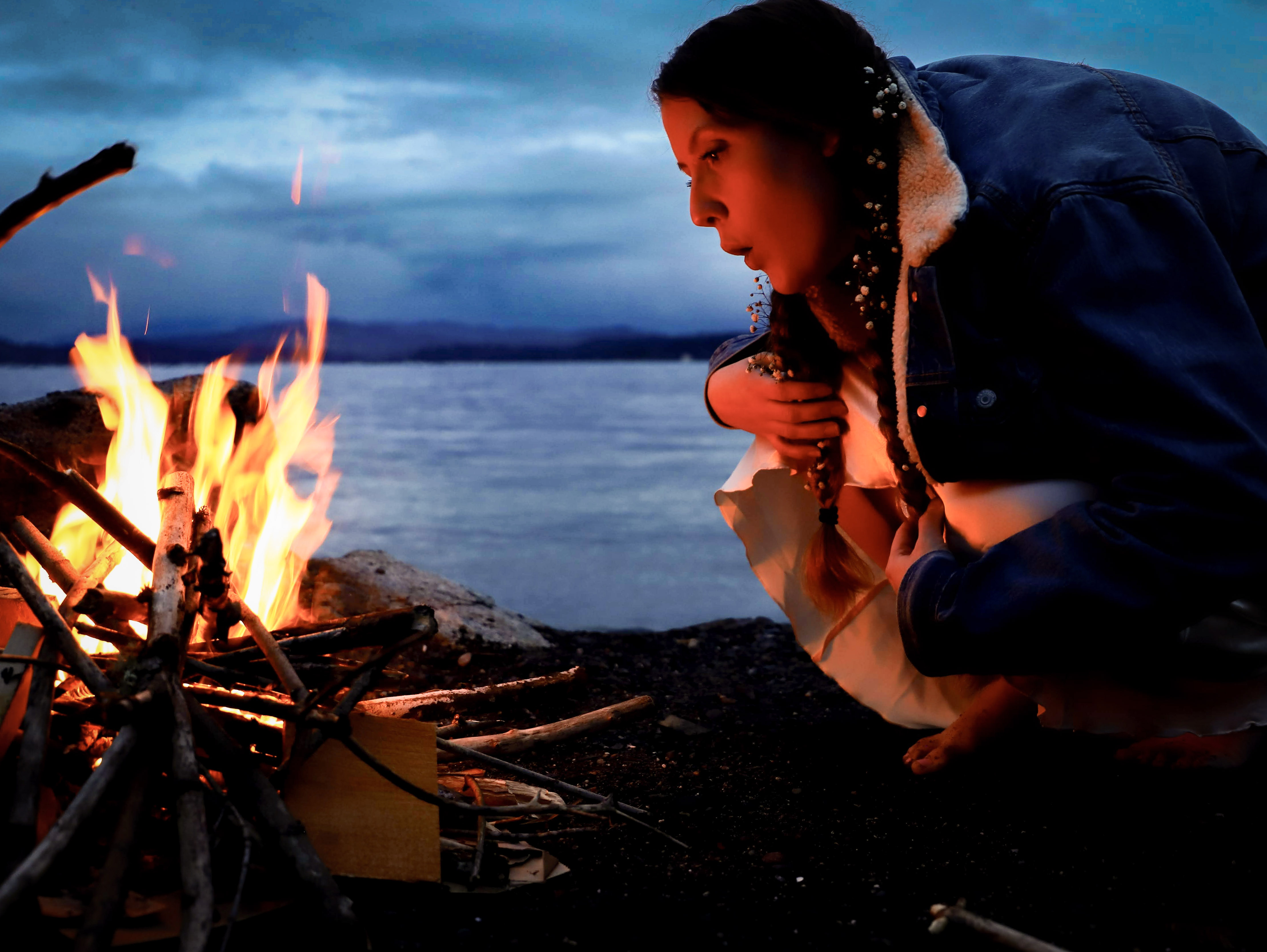 caption: In this file photo, a woman named Rose blows to keep the fire alive at a park next to Lake Washington in Seattle.