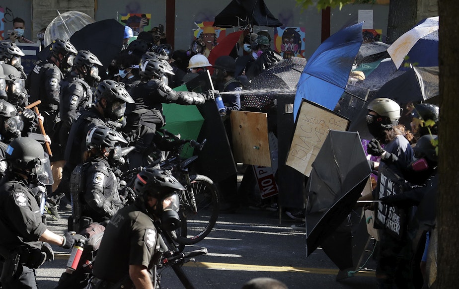 caption: Police pepper spray protesters, Saturday, July 25, 2020, near Seattle Central Community College in Seattle. A large group of protesters were marching Saturday in Seattle in support of Black Lives Matter and against police brutality and racial injustice.