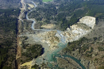 caption: FILE - In this March 24, 2014 file photo, the massive mudslide that killed 43 people in the community of Oso, Wash., is shown from the air. The community will mark the one-year anniversary of the slide on March 22, 2015. 