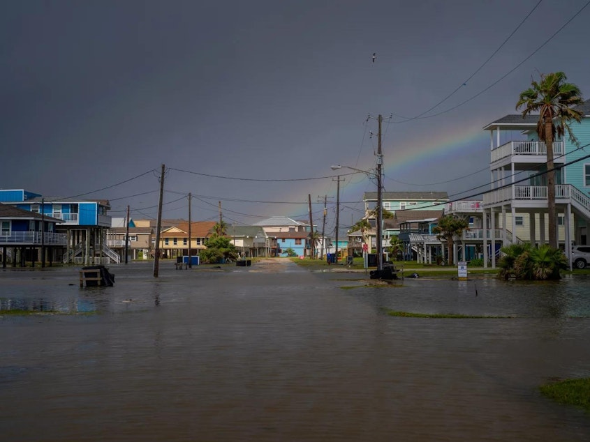 caption: A rainbow appears behind a flooded neighborhood in Jamaica Beach, Texas, on Thursday.
