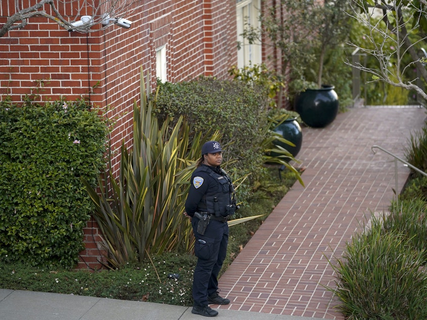 caption: A police officer stands outside the home of House Speaker Nancy Pelosi and her husband Paul Pelosi in San Francisco on Friday, after Paul was attacked and severely beaten by an assailant who broke into their home early Friday.