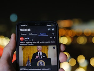 caption: Russia blocked Facebook on Friday citing "discrimination" against state-sponsored media. Here a smartphone user in Moscow watches a Facebook clip of U.S. President Joe Biden on Friday, Feb. 25, 2022.