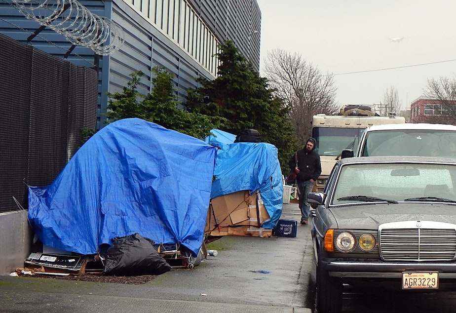 caption: Homeless encampment along a road in the Sodo area of Seattle.