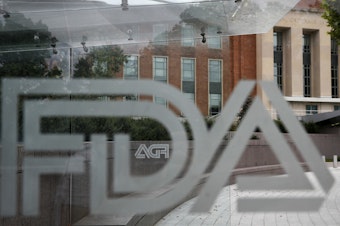 caption: FILE - This Thursday, Aug. 2, 2018, file photo shows the U.S. Food and Drug Administration building behind FDA logos at a bus stop on the agency's campus in Silver Spring, Md.