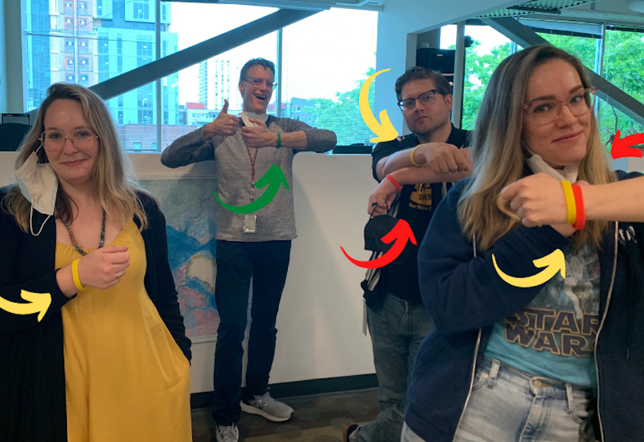 caption: KUOW's Katie Campbell, Bill Radke, Dyer Oxley, and Libby Denkmann show off their wristbands — worn around the KUOW office to show individual comfort levels as people navigate pandemic social settings. 