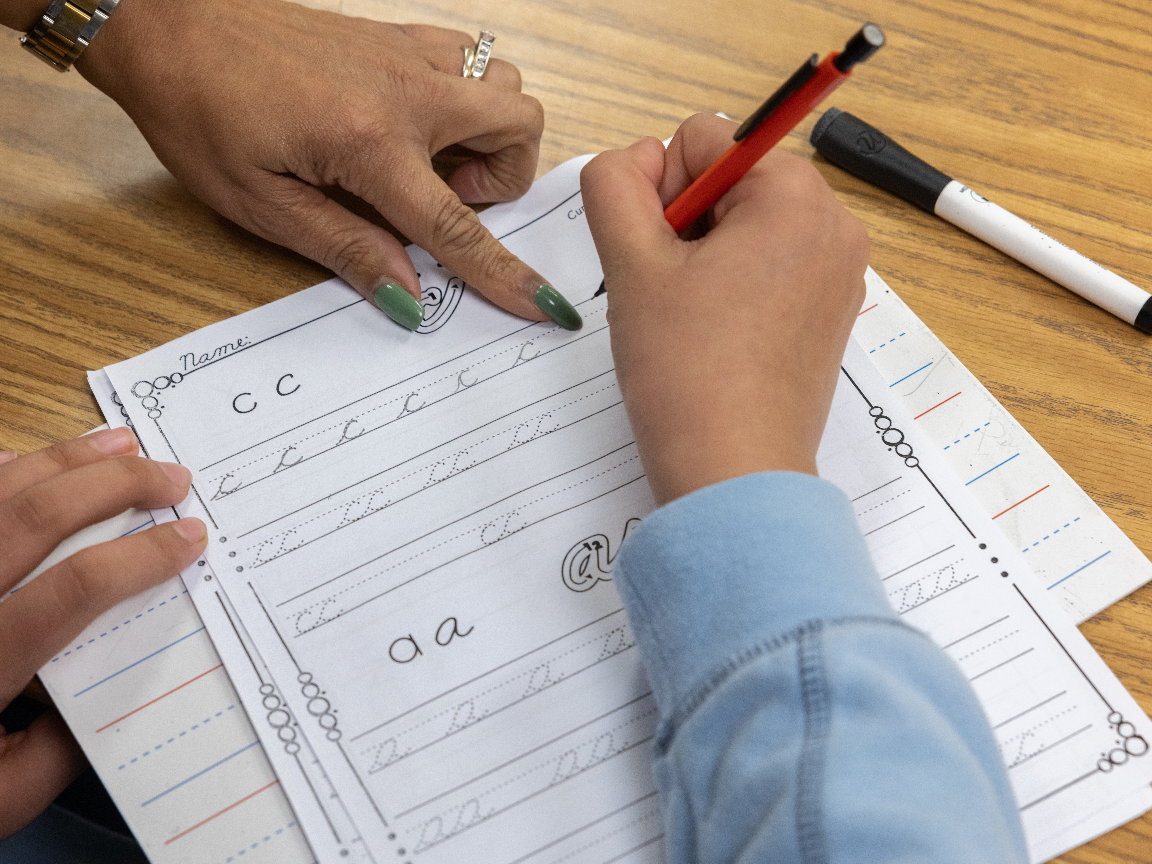 caption: Teacher Sherisse Kenerson helps a student during after-school cursive club at Holmes Middle School in Alexandria, Va.