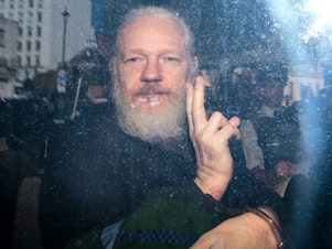 caption: Julian Assange gestures seen inside a police vehicle on his arrival at Westminster Magistrates court in London on April 11. The WikiLeaks founder was sentenced to 50 weeks in prison by a British judge on Wednesday.