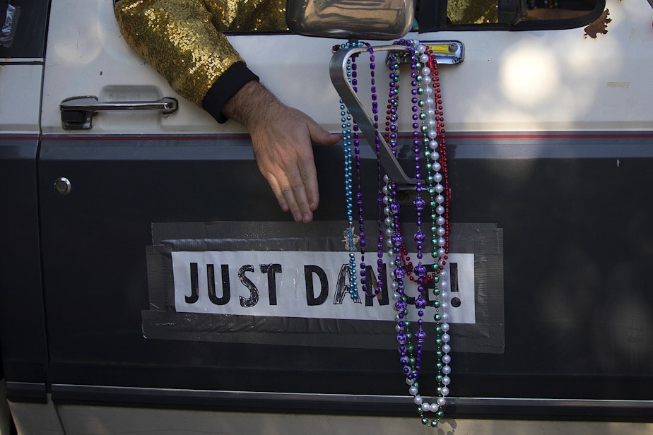 caption: Member of the Seattle Quarantine Parade, Jordan Crump, taps the side of the truck along to the music while driving through the Wallingford neighborhood on Friday, May 8, 2020, in Seattle. 