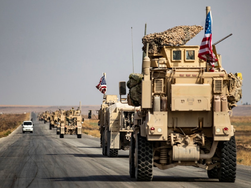 caption: U.S. military vehicles drive on a road in the town of Tal Tamr on Sunday after pulling out of a base in northern Syria. Defense Secretary Mark Esper says some troops may remain in northeast Syria to secure oil fields.