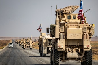 caption: U.S. military vehicles drive on a road in the town of Tal Tamr on Sunday after pulling out of a base in northern Syria. Defense Secretary Mark Esper says some troops may remain in northeast Syria to secure oil fields.