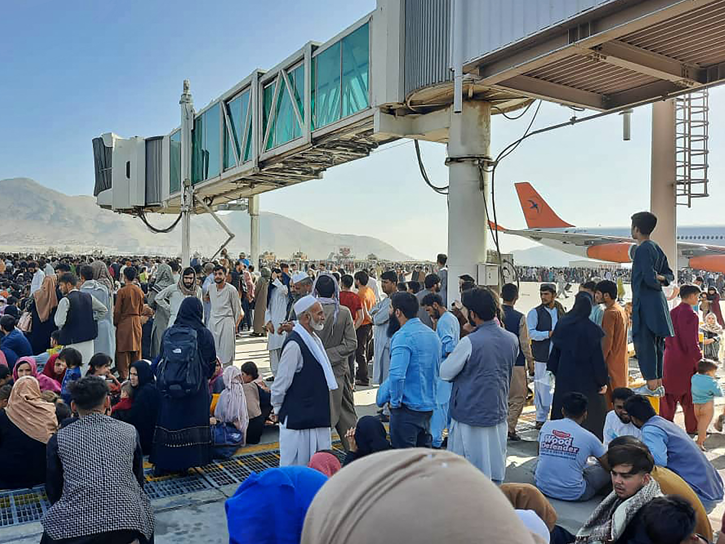 caption: Afghans crowd the tarmac of the Kabul airport on Monday to flee the country. Thousands of people mobbed the city's airport trying to flee the group's feared hardline brand of Islamist rule.