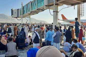 caption: Afghans crowd the tarmac of the Kabul airport on Monday to flee the country. Thousands of people mobbed the city's airport trying to flee the group's feared hardline brand of Islamist rule.