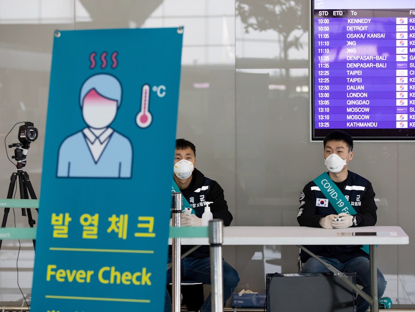 caption: South Korean soldiers wearing protective masks sit at a temperature screening point at Incheon International Airport, South Korea, on March 9.