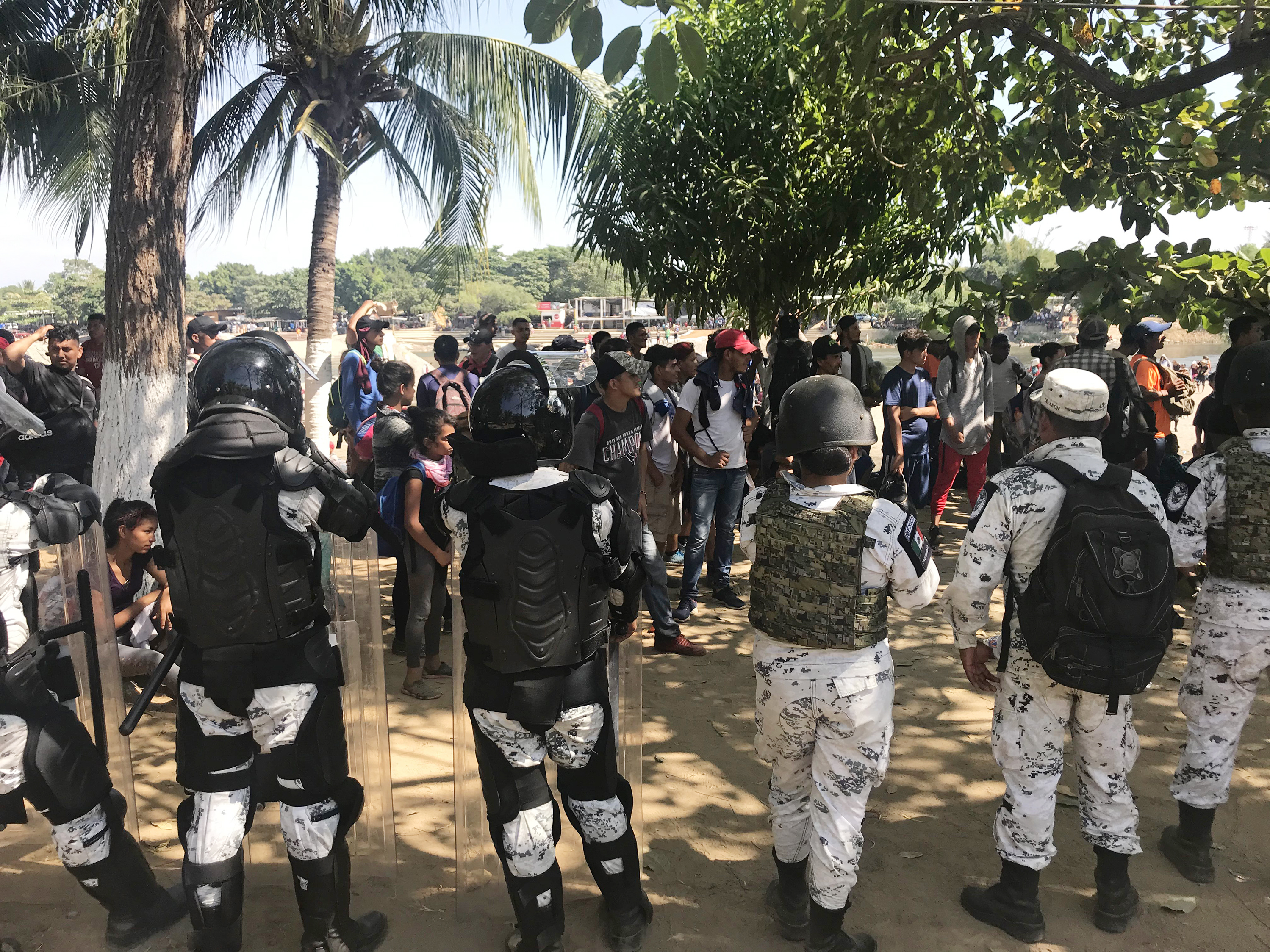caption: Mexico's National Guard prevents migrants who walked across the river from making their way further into Mexico.