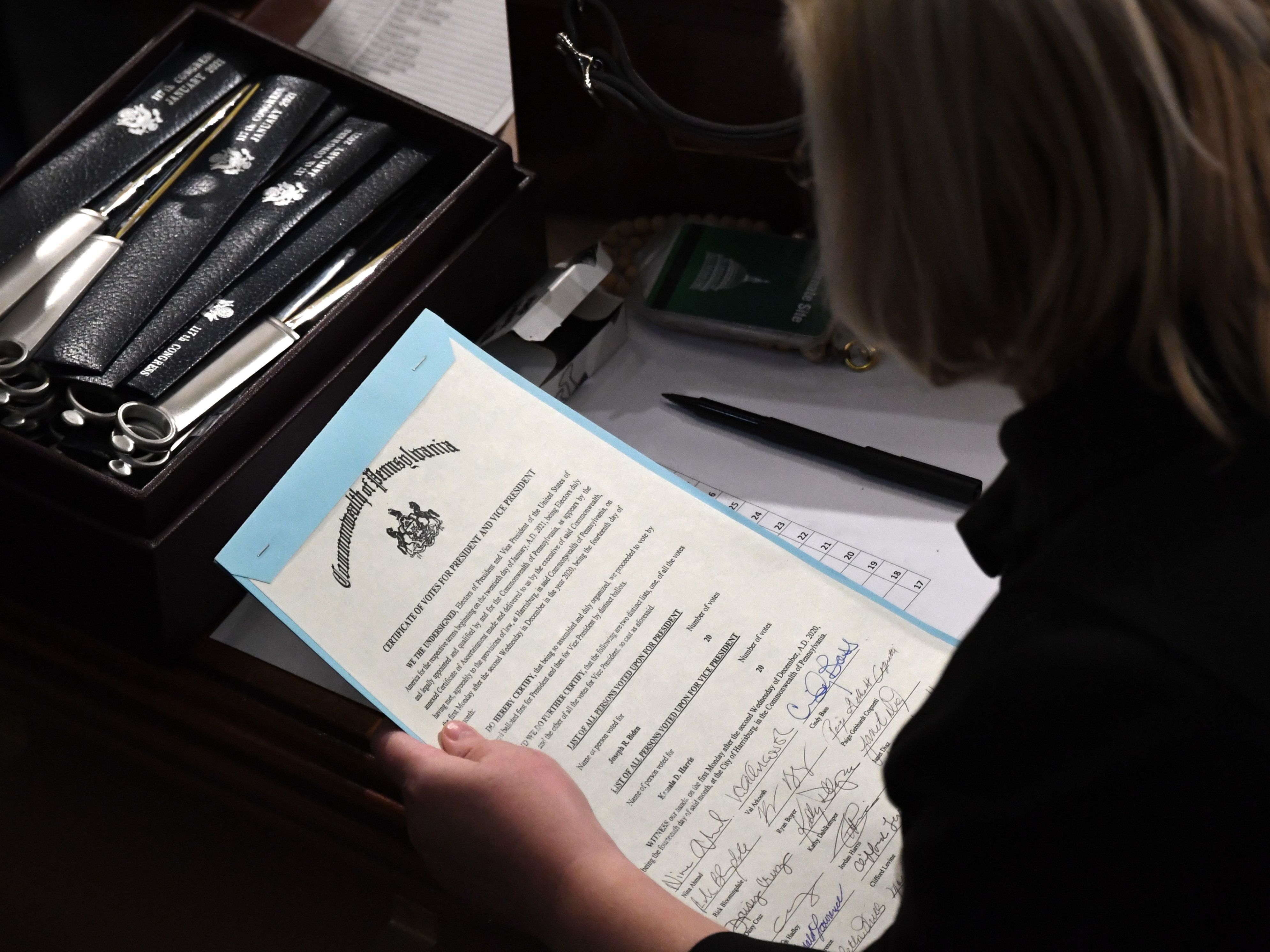 caption: A person holds the certificate of electoral votes from Pennsylvania during a joint session of Congress early on Jan. 7, 2021, as the counting of electoral votes resumed after the riot at the U.S. Capitol.