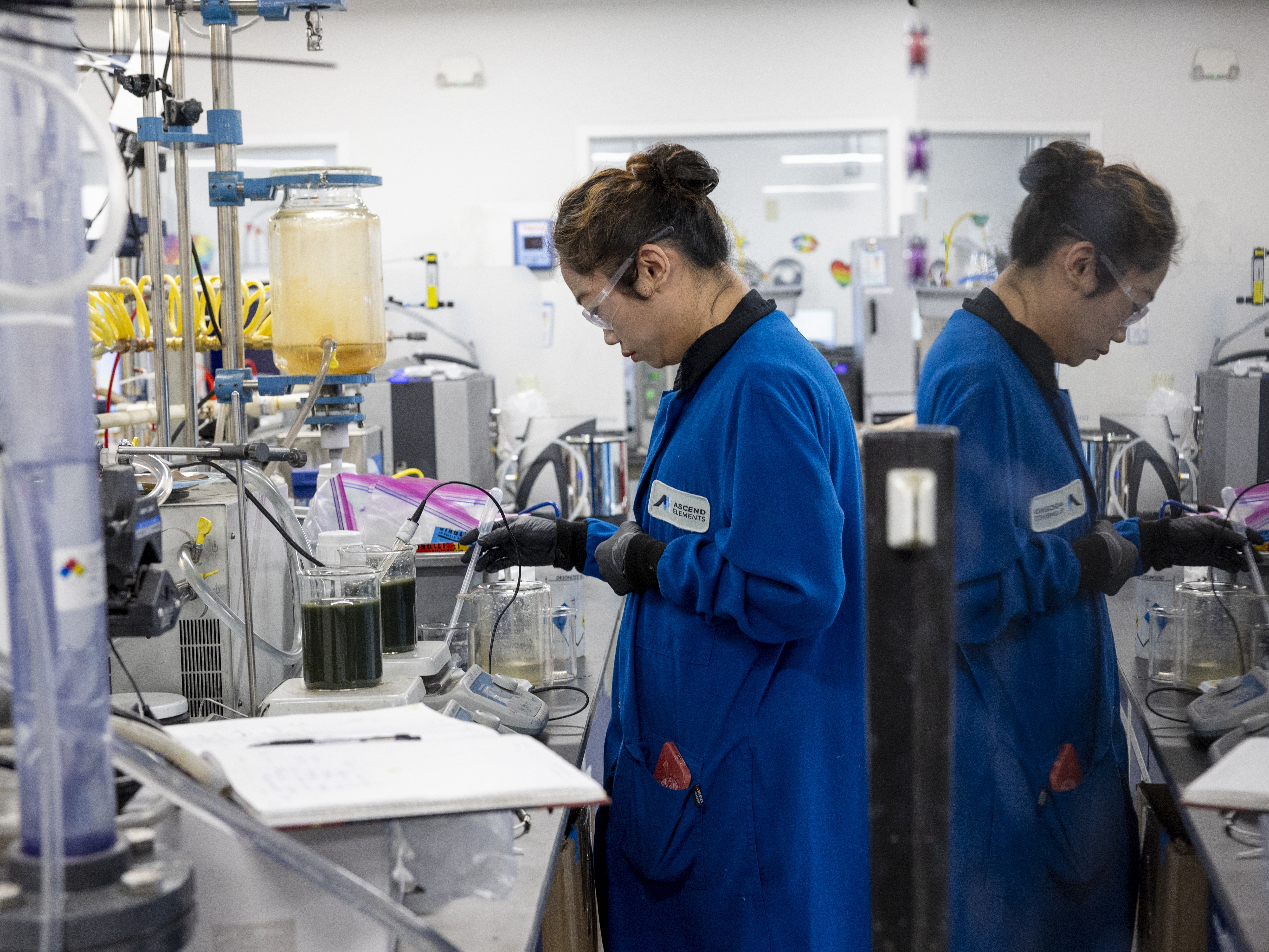 caption: Xin Li, a research and development associate, works at Ascend Elements in Westborough, Mass., on June 13. The company is one of several that are scrambling to build recycling plants that can recover minerals from electric vehicle batteries without using dirty techniques like burning them — or wasting energy by shipping them overseas.