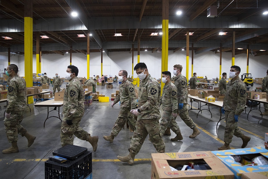 caption: Washington National Guard soldiers walk through the Food Lifeline Covid Response Center on Tuesday, April 21, 2020,  along East Marginal Way South in Seattle. “What makes this particular response different is just the very steep increase in need in our communities,” said Amythst Shipman, director of operations strategy at Food Lifeline. 