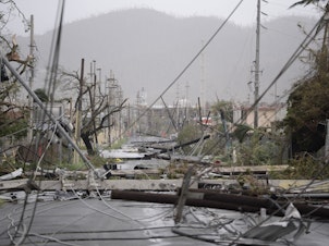 caption: In this Sept. 20, 2017 file photo, electricity poles and lines lie toppled on the road after Hurricane Maria hit the eastern region of the island in Humacao, Puerto Rico.
