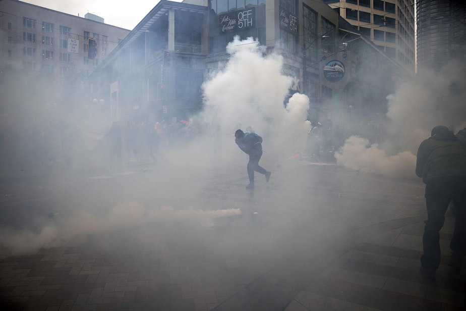 caption: A protester runs from tear gas at the intersection of 5th and Pine Streets on Saturday, May 30, 2020, in Seattle.