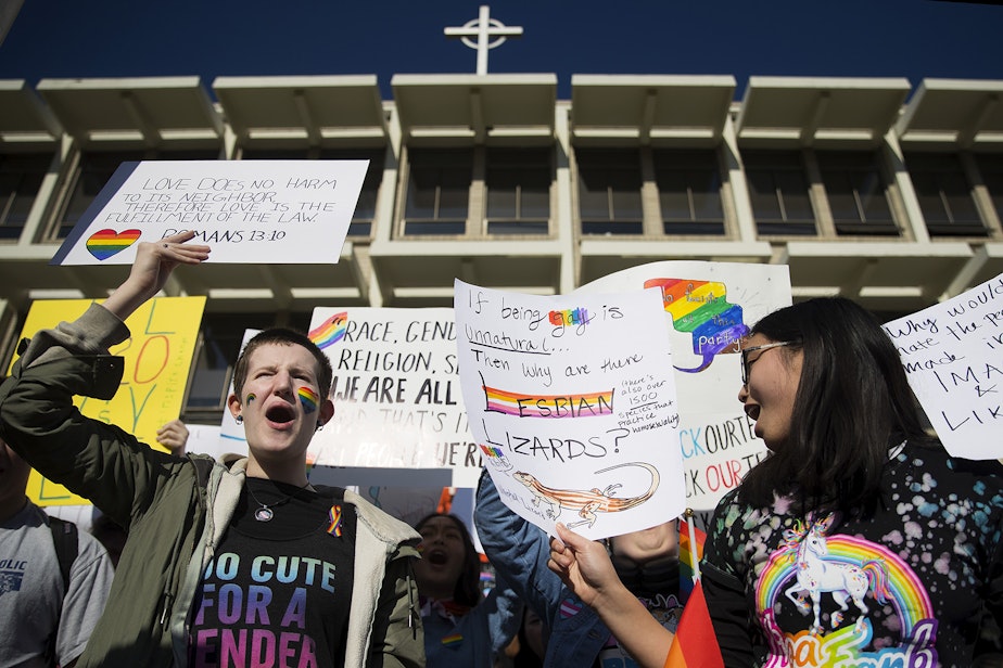 caption: Lyn Shaffer, a 16-year-old high school junior, left, chants with classmates during a walkout to protest the departure of two LGBT educators on Tuesday, February 18, 2020, at Kennedy Catholic High School in Burien. 