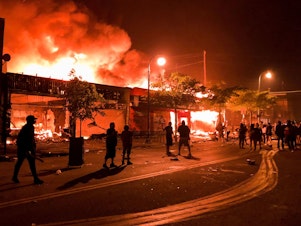 caption: Flames rise from a liquor store and shops near the Third Police Precinct on May 28, 2020 in Minneapolis, Minnesota, during a protest over the death of George Floyd, an unarmed black man, who died after a police officer kneeled on his neck for several minutes.